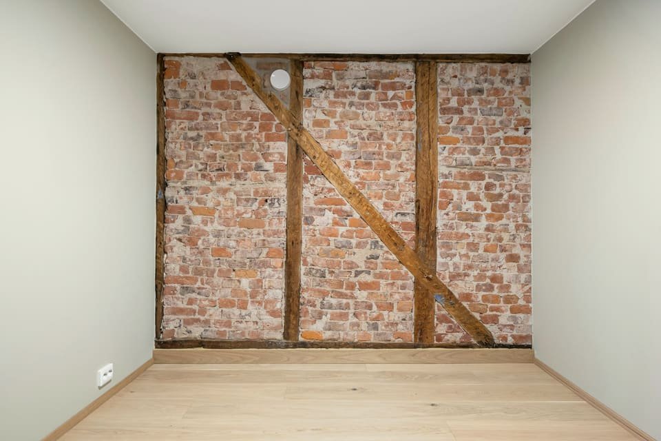 Après travaux : mur en briques et pans de bois remis à nu, murs repeints en blanc et parquet en chêne clair
